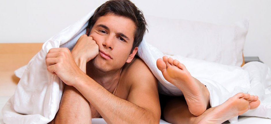 man's lying on a bed with the sole of his partner on his face
